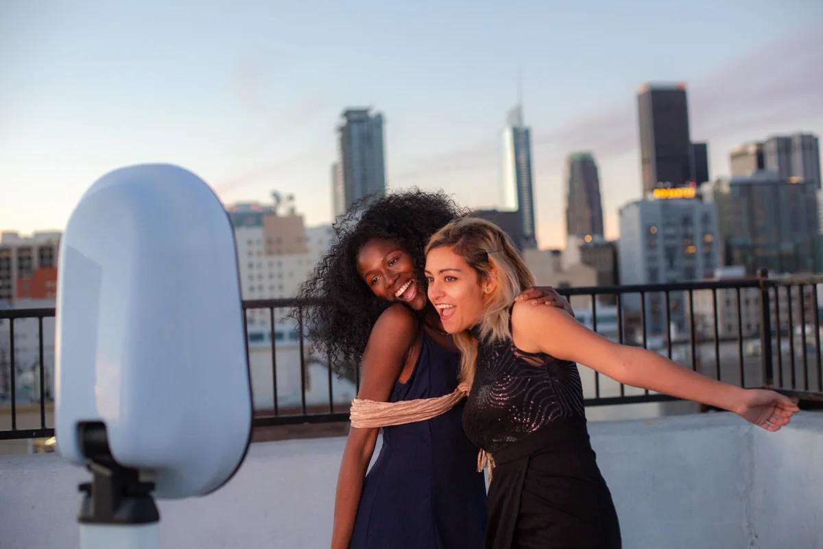 Two friends enjoying the photo booth on a rooftop